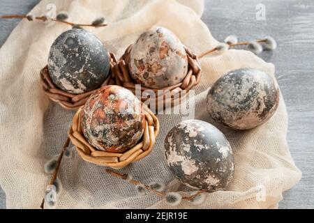 Composition de Pâques - plusieurs oeufs en marbre peints avec des teintures naturelles dans des paniers en osier. Banque D'Images