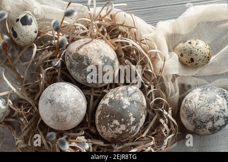 Composition Pâques - plusieurs œufs en marbre peints avec des teintures naturelles dans un nid en papier sur la table, vue du dessus. Banque D'Images