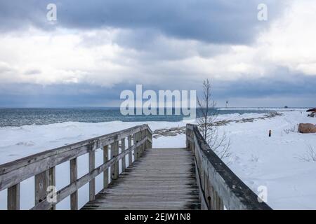 Un vieux pont en bois traverse une section du front de mer gelé de la baie Georgienne à Collingwood, en Ontario. Le ciel au-dessus est menaçant et sombre, avec un hiver Banque D'Images