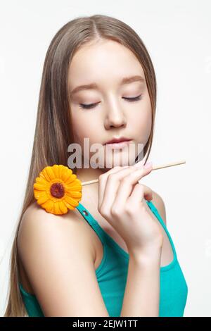 Adolescente avec une fleur en mains. Concept de dent douce. Banque D'Images