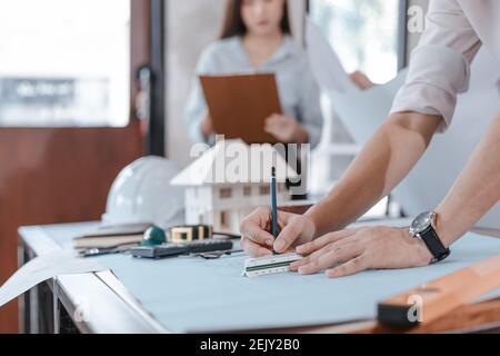 les ingénieurs tenant un stylo pointant vers un bâtiment et dessinant un plan de construction de dépenses comme guide pour les constructeurs avec des détails. Concevoir et écrire des ingénieurs b Banque D'Images