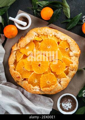 Vue de dessus de la caraway et de la tarte orange sur le papier de cuisson sur fond de ciment noir.Recette pour la saison d'hiver et les idées de noël - tartelez avec une pâtisserie au carvi et des oranges, des mandarines ou des mandarines. Banque D'Images