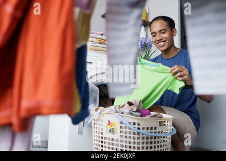 un beau mari asiatique qui met des vêtements sales un par un dans lave-linge et linge à la maison Banque D'Images