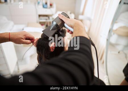 Styliste professionnelle utilisant des outils de coiffure pour faire des boucles Banque D'Images