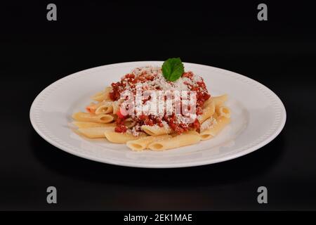 Mise au point sélective et gros plan d'une savoureuse assiette de pâtes cuites à la sauce bolognaise et au fromage sur fond sombre. Pâtes et concept de style de vie. Banque D'Images