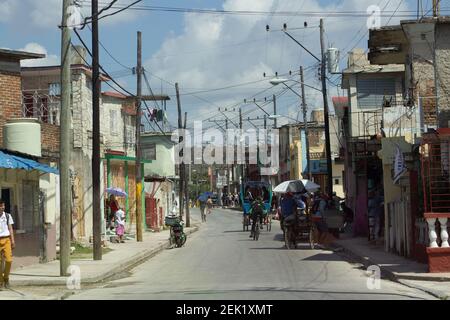 HOLGUIN, CUBA - 18 FÉVRIER; 2019 rangées de petits magasins avec lignes électriques et cyclistes Banque D'Images