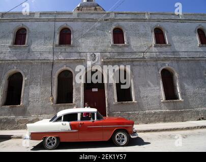 HOLGUIN, CUBA - 18 FÉVRIER; 2020 voiture classique rouge et blanche garée à l'extérieur du bâtiment de la vieille ville Banque D'Images