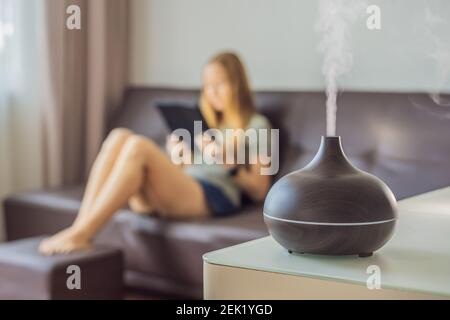 Concept d'aromathérapie. Diffuseur et humidificateur d'huile essentielle à ultrasons en bois électrique. Diffuseur d'arôme ultrasonique pour la maison. Femme se reposant à Banque D'Images