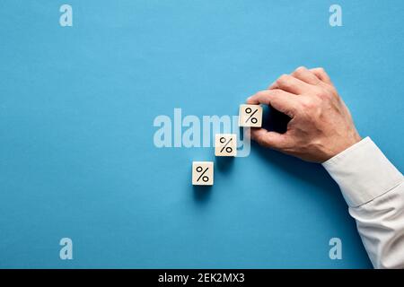 Homme d'affaires organisant des blocs de bois empilant comme escalier avec le symbole de pourcentage ou de pourcentage. Augmentation de la remise sur les ventes ou de l'hypothèque et financière Banque D'Images