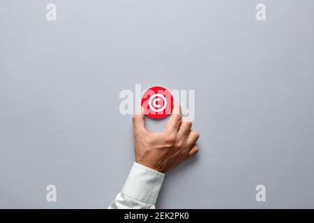 Main d'homme d'affaires portant un badge rouge avec symbole de copyright. Les droits de propriété et la protection des brevets de marque dans le concept d'entreprise. Banque D'Images