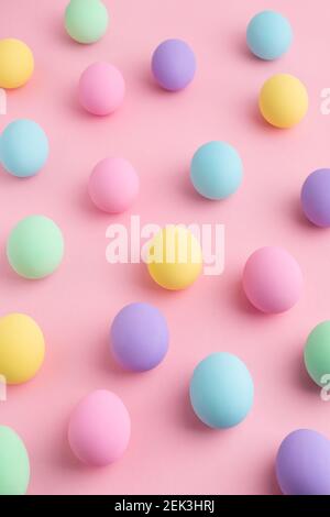 Œufs de Pâques de couleur pastel dispersés sur fond rose. Motif abstrait coloré pour le jour de Pâques, pose à plat. Banque D'Images