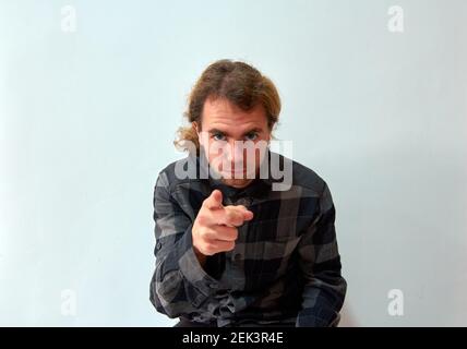 Beau caucasien homme avec de longs cheveux pointant vers l'appareil photo avec son doigt sur fond blanc Banque D'Images