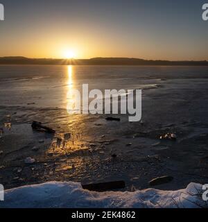 Lever de soleil sur un lac gelé avec des morceaux de glace et de réflexion, paysage naturel avec espace de copie, mise au point sélectionnée Banque D'Images