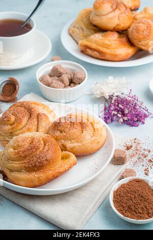 Gâteaux faits maison, petits pains à l'escargot au sucre sur fond bleu doux. Vue latérale, verticale. Banque D'Images