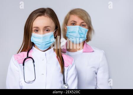 Concept de santé, de médecine et de pandémie - gros plan de deux femmes caucasiennes médecins ou scientifiques en masque protecteur, travailleurs médicaux à l'hôpital sur gris Banque D'Images