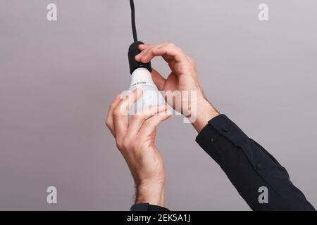 Des mains mâles vissent une ampoule LED dans le support Banque D'Images