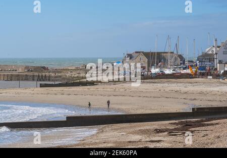 Lyme Regis, Dorset, Royaume-Uni. 23 février 2021. Météo au Royaume-Uni : les habitants apprécient le soleil de printemps et le ciel bleu vif lors d'une matinée ventée à Lyme Regis. Les entreprises de la ville attendent avec impatience la levée progressive du confinement à temps pour la saison estivale. Credit: Celia McMahon/Alamy Live News Banque D'Images