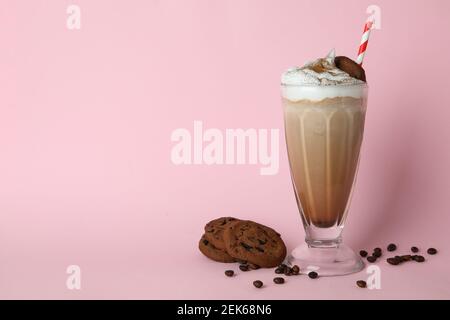 Un verre de milkshake, de graines de café et de biscuits sur fond rose Banque D'Images