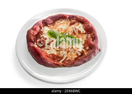 Pizza margherita rouge avec pâte colorée et betterave rouge. Recouverte de mozzarella, de tomates et de feuilles de basilic. Isolée sur blanc Banque D'Images