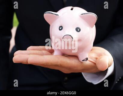 L'homme d'affaires nourrit la banque de porc avec le billet de banque allemand - concept d'économie fonds de prêt investissant de l'argent Banque D'Images