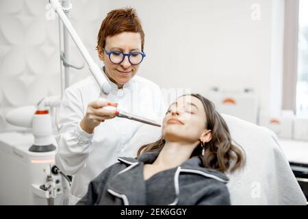 Cosmétologue faisant la procédure de facélifting laser dans la clinique de beauté Banque D'Images