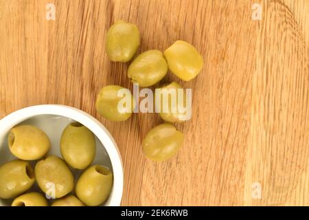 Quelques délicieuses olives vertes épicées bio marinées sur fond de plateau en bambou. Banque D'Images