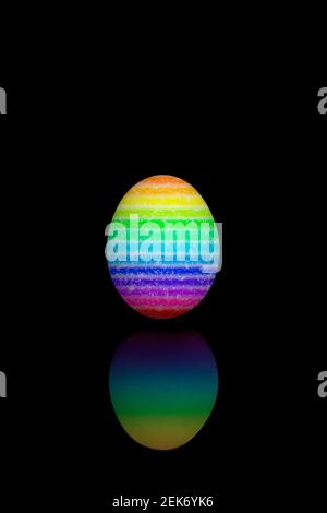 Oeuf de Pâques peint avec différentes couleurs arc-en-ciel, isolé sur bakcground noir. Banque D'Images