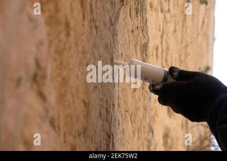 Un agent de préservation injecte un coulis liquide à base de calcaire dans les fissures des pierres vieilles de 2,000 ans du mur de l’Ouest pour les préserver et les renforcer le 23 février 2021, à Jérusalem, en Israël. Les conservateurs de l'Autorité des Antiquités d'Israël ont commencé le travail de conservation pour préparer le mur occidental pour la Pâque. Cette section du mur de soutènement du complexe du Mont du Temple est inspectée et nettoyée deux fois par an, une fois avant la Pâque et l'autre fois avant Rosh Hashanah la nouvelle année juive. Banque D'Images