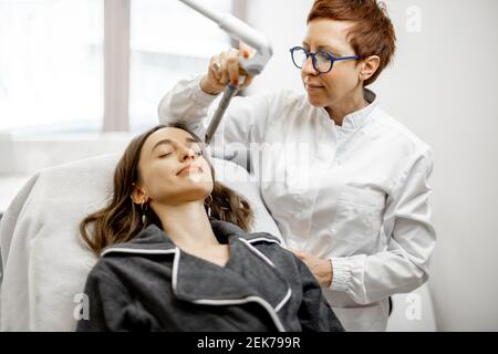 Cosmétologue faisant la procédure de facélifting laser dans la clinique de beauté Banque D'Images