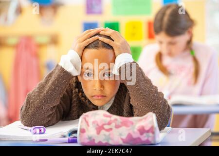 Jeune fille à la recherche d'un appareil photo dans une salle de classe d'école Banque D'Images