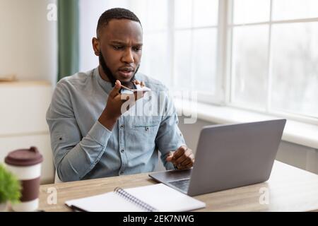 Homme d'affaires noir utilisant le téléphone avec l'application Voice Assistant dans Office Banque D'Images