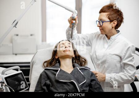 Cosmétologue faisant la procédure de facélifting laser dans la clinique de beauté Banque D'Images