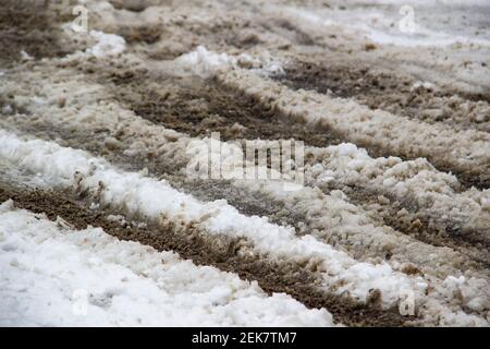 Neige sale mélangée à propre sur la route. La neige fond avec du sable. Banque D'Images