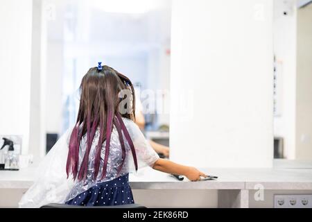 une petite fille teint ses cheveux violets dans un salon de coiffure Banque D'Images