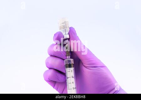 Brasov, Roumanie - 21 février 2021 : médecin utilisant le vaccin Pfizer-BioNTech Covid-19 sur fond blanc. Banque D'Images