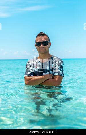 Un gars heureux dans un t-shirt dans la mer. Concept d'été. Banque D'Images