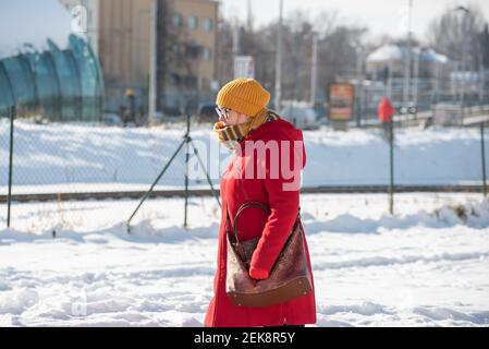 Prague, République tchèque. 02-23-2021. Une femme colorée avec masque marche dans le centre-ville de Prague par une froide journée d'hiver. Banque D'Images