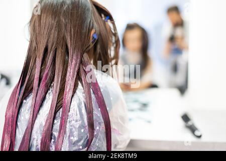 une petite fille teint ses cheveux violets dans un salon de coiffure Banque D'Images