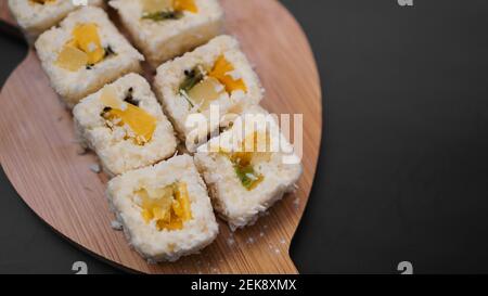 Livraison de sushis. Petits pains sucrés à base de riz, ananas, kiwi et mangue. Roule sur fond noir Banque D'Images