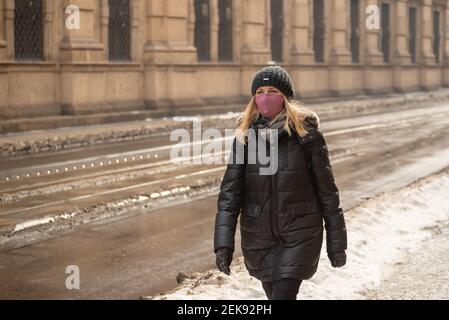 Prague, République tchèque. 02-23-2021. Une jeune femme avec masque marche dans le centre-ville de Prague par une froide journée d'hiver. Banque D'Images