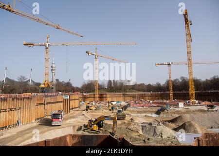 Munich, Allemagne. 23 février 2021. Les travailleurs de la construction travaillent avec des véhicules sur le chantier du jardin SAP, le nouveau terrain de hockey sur glace et de basket-ball, tandis que la Tour olympique et le stade olympique sont visibles en arrière-plan. Financé par Red Bull, le hall multifonctionnel, qui sera appelé SAP Garden, devrait être achevé en 2022. Credit: Matthias balk/dpa/Alay Live News Banque D'Images