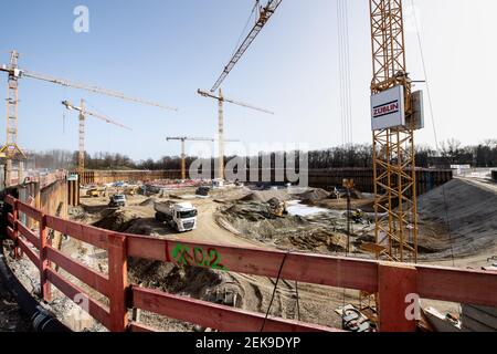 Munich, Allemagne. 23 février 2021. Les travailleurs de la construction travaillent avec des véhicules sur le chantier du jardin SAP, le nouveau terrain de hockey sur glace et de basket-ball, tandis que la Tour olympique et le stade olympique sont visibles en arrière-plan. Financé par Red Bull, le hall multifonctionnel, qui sera appelé SAP Garden, devrait être achevé en 2022. Credit: Matthias balk/dpa/Alay Live News Banque D'Images