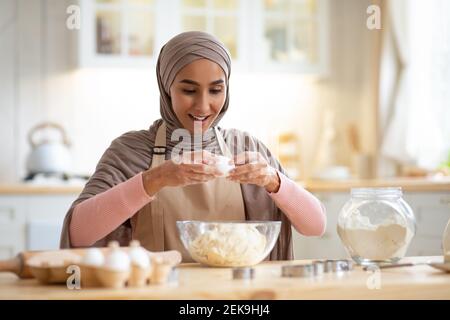 Jeune femme musulmane dans hijab et Apron cuisson dans la cuisine Banque D'Images