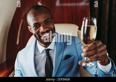 Homme d'affaires élégant avec champagne en avion Banque D'Images