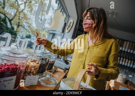 Une femme mûre se cache pour ramasser des aliments lors de ses achats dans un magasin sans déchets pendant une pandémie Banque D'Images