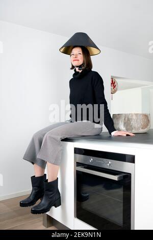 Femme mûre avec abat-jour noir sur la tête comptoir de cuisine à la maison Banque D'Images