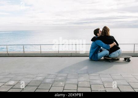 Couple assis au sol dans un skateboard, face à la mer Banque D'Images