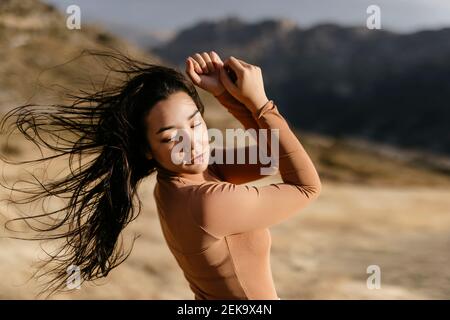 Jeune femme dansant dans le vent au coucher du soleil Banque D'Images