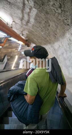 Homme descendant sur les escaliers mécaniques dans le métro de Mexico Banque D'Images