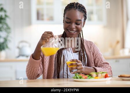 Portrait d'une belle femme noire mangeant un petit déjeuner sain dans la cuisine à la maison Banque D'Images